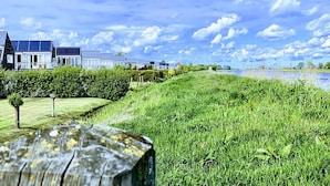 A residential area with houses, a grassy field, and a body of water. - Grou Getaway With Bikes & Whirlpool (Grou)