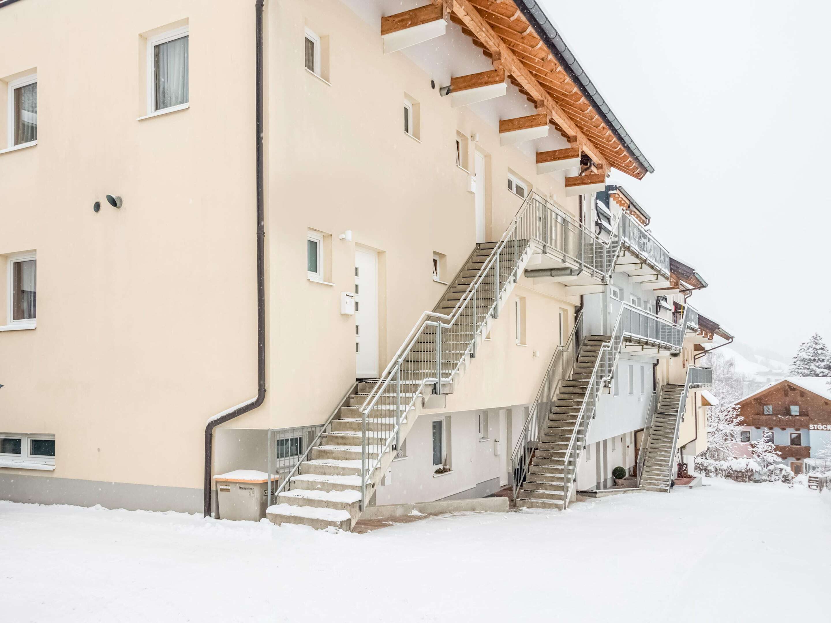 A multi-story building with external staircases and balconies, surrounded by snow.