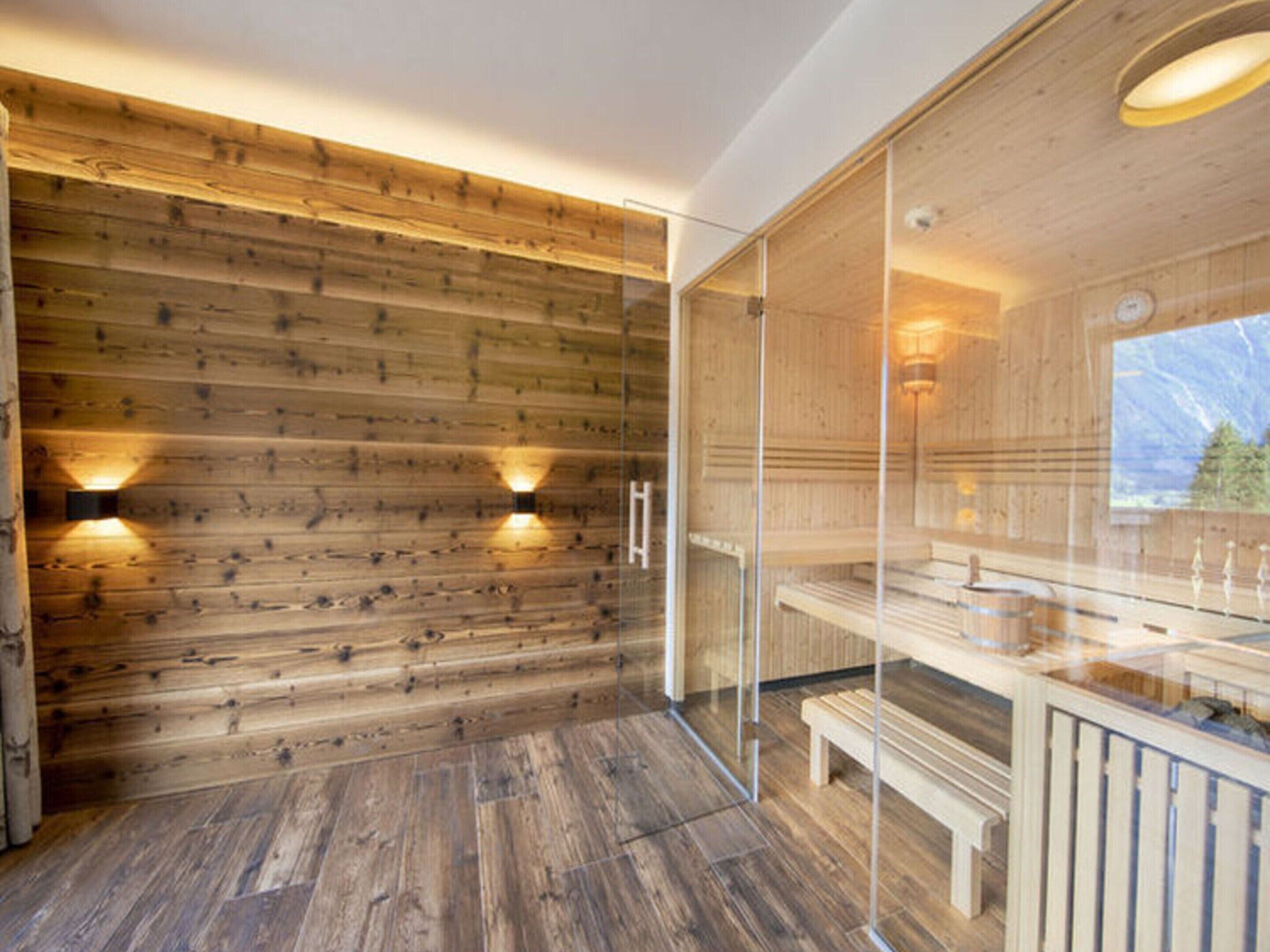 Eine moderne Holz-Blockhütte mit Glaswand, Holzbänken und Holzboden.