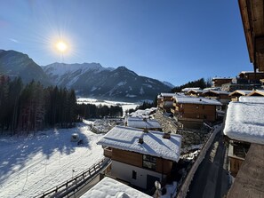 Un pueblo cubierto de nieve con edificios de madera, cielo despejado y montañas al fondo.