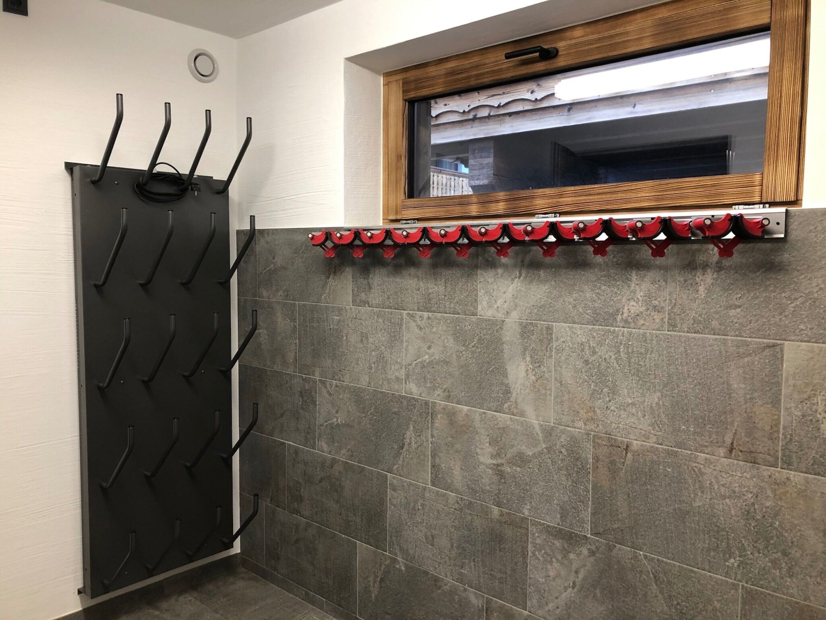 Quarto com um porta-casacos preto, janela com moldura de madeira e parede revestida de azulejos.