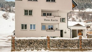 A multi-story building named Haus Karin with a stone wall in front, set against a snowy landscape. - Apartment in Kappl Right by the ski Lift (Kappl)