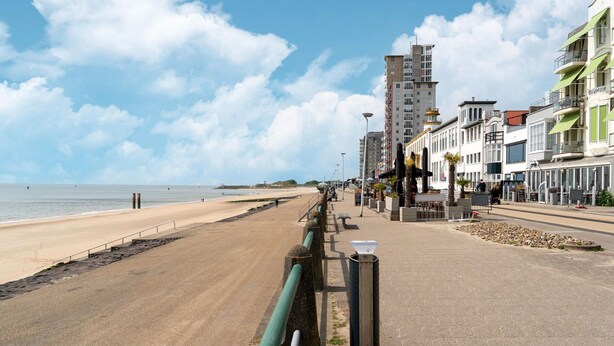A coastal promenade with a sandy beach, a paved walkway, and buildings with balconies overlooking the sea. - Vlissingen Home Near the Beach (Vlissingen)