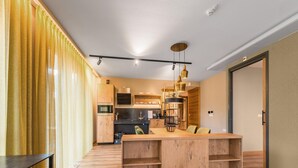 A modern kitchen with wooden cabinets, a central island, and pendant lighting.