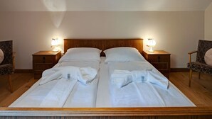 A double bed with white linens and two bedside tables with lamps, in a room with wooden flooring and walls. - Apartment in Mooswald in Carinthia With Pool (Fresach)