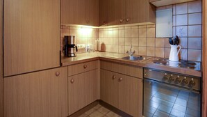 A kitchen with wooden cabinets, a stainless steel stove, and a tiled backsplash. - Apartment in Mooswald in Carinthia With Pool (Fresach)