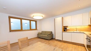 Un apartamento moderno con comedor, sofá, cocina con armarios blancos y un ventanal grande.