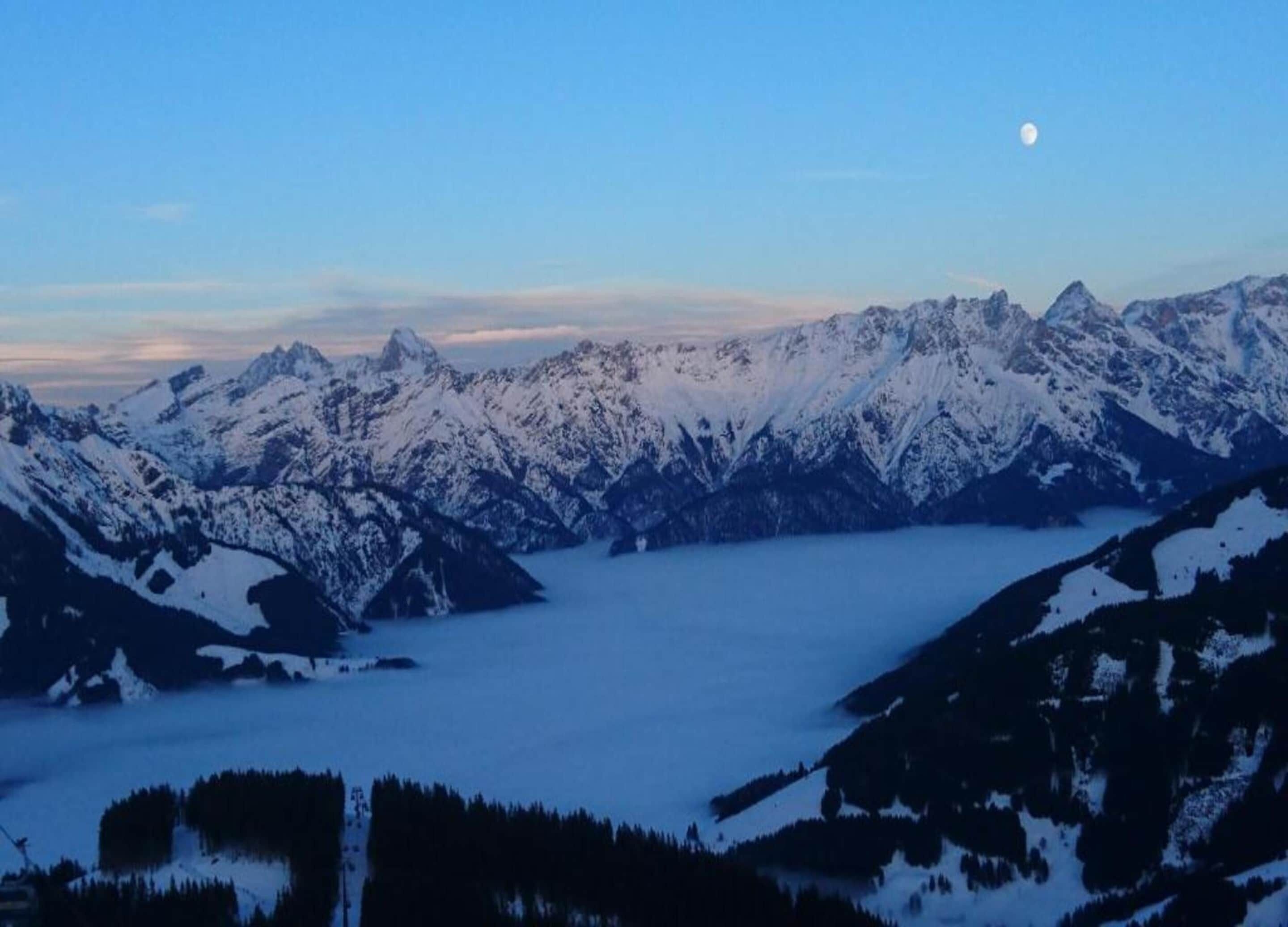 A mountain landscape with snow-covered peaks and a lake at the base.