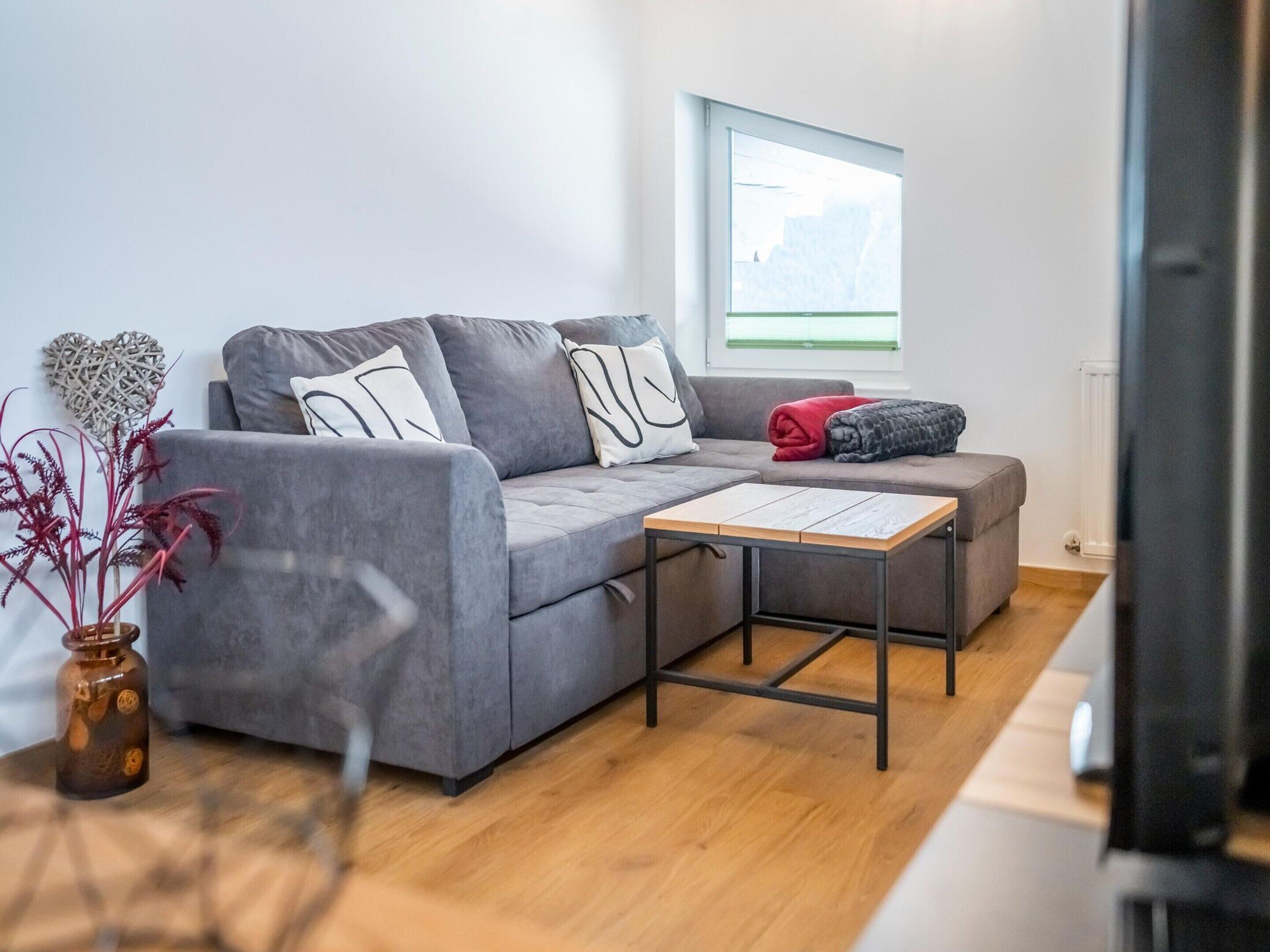 Un salon moderne avec un canapé gris, une petite table en bois et une plante en pot.