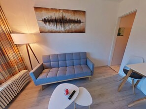 A modern living room with a sofa, a coffee table, a lamp, a painting, and a radiator.