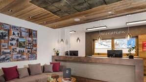 A reception area with a wooden ceiling, a reception desk, a sofa, and a coffee table. - Luxurious Flat in a Great Location on the Hochkonig (Muehlbach Am Hochkoenig)