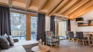 A modern living room with a sofa, a plaid armchair, and a dining area with a table and chairs. - Luxurious Flat in a Great Location on the Hochkonig (Muehlbach Am Hochkoenig)