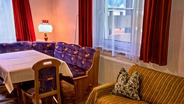 A cozy room with a dining table, blue patterned sofa, and a striped sofa with leopard print pillows. - Pleasant Holiday Home in Langenfeld With Balcony (Laengenfeld)