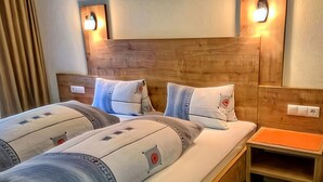 A hotel room with two beds, wooden headboard, bedside tables, and wall-mounted lights. - Pleasant Holiday Home in Langenfeld With Balcony (Laengenfeld)