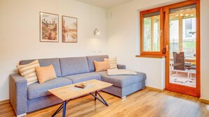 Una sala de estar moderna con un sofá gris, una mesa de centro de madera y un ventanal con vistas al exterior.