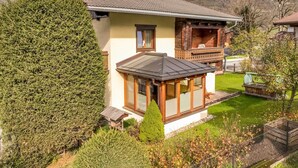 Una casa con techo inclinado, balcón y jardín bien cuidado.