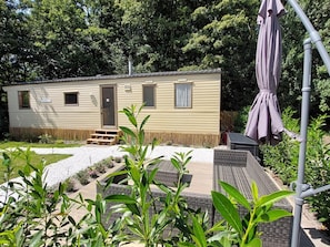 A mobile home with a door, windows, and a small porch area.