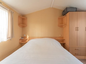 A bedroom with a single bed, wooden wardrobe, and built-in shelves.