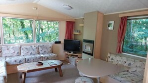 Uma sala de estar aconchegante com sofá, mesa de centro, televisão e uma mesa.