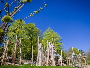 A playground with climbing structures and a slide, surrounded by trees and grass.
