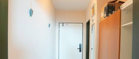 A hallway with a wooden floor, a door at the end, and a small table with a keyboard.