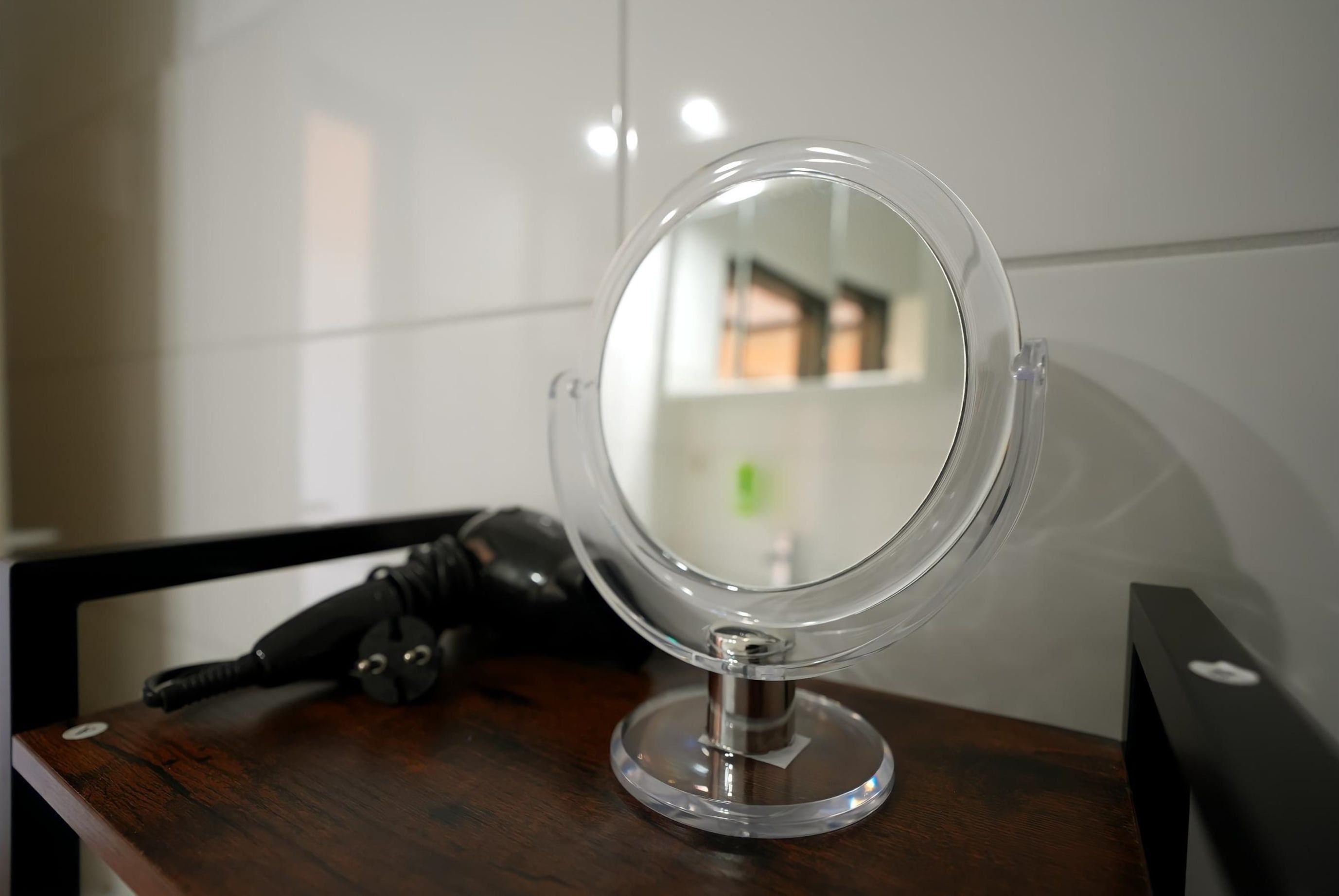 A round mirror on a wooden surface with a black object beside it.