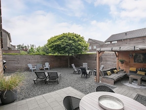 A patio area with outdoor furniture, a pergola, and a large tree providing shade.