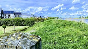 A residential area with houses, a grassy field, and a body of water. - Holiday Home in Grou With Bubble Bath (Grou)