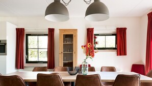 A dining area with a large table, six chairs, and two pendant lights.
