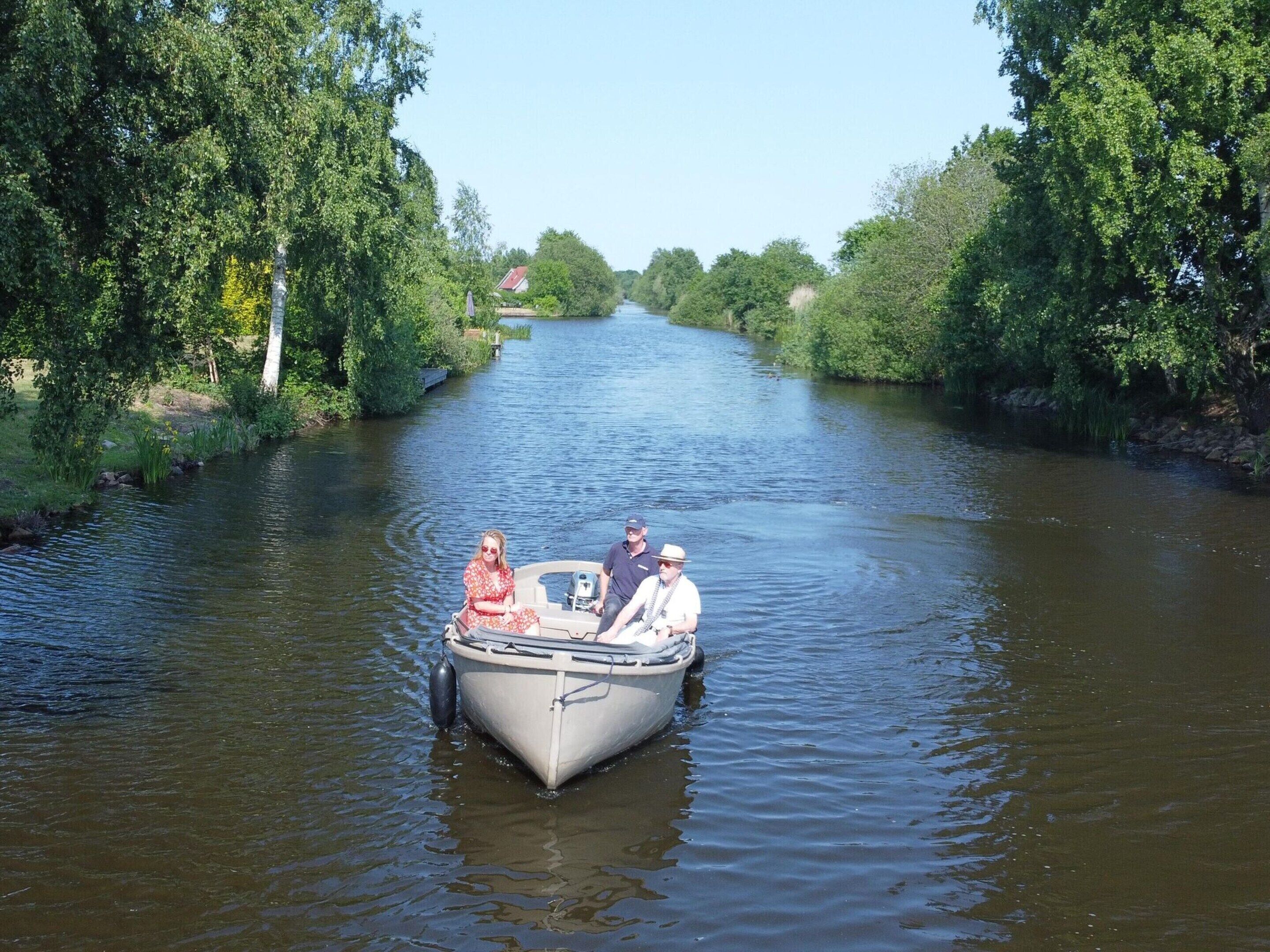 A narrow waterway with a small boat carrying three people.