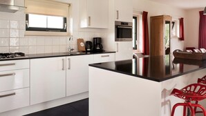 A modern kitchen with white cabinets, a black countertop, a built-in oven, and a coffee maker.
