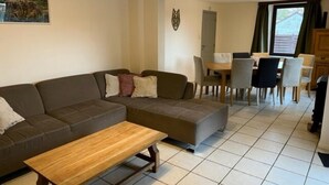 En stue med en hjørnesofa, et træsofabord og et spiseområde med bord og stole.