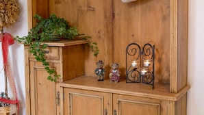 A wooden cabinet with a shelf holding a potted plant, two small teddy bears, and a candle holder with candles. - Apartment With Sauna in Radstadt (Radstadt)