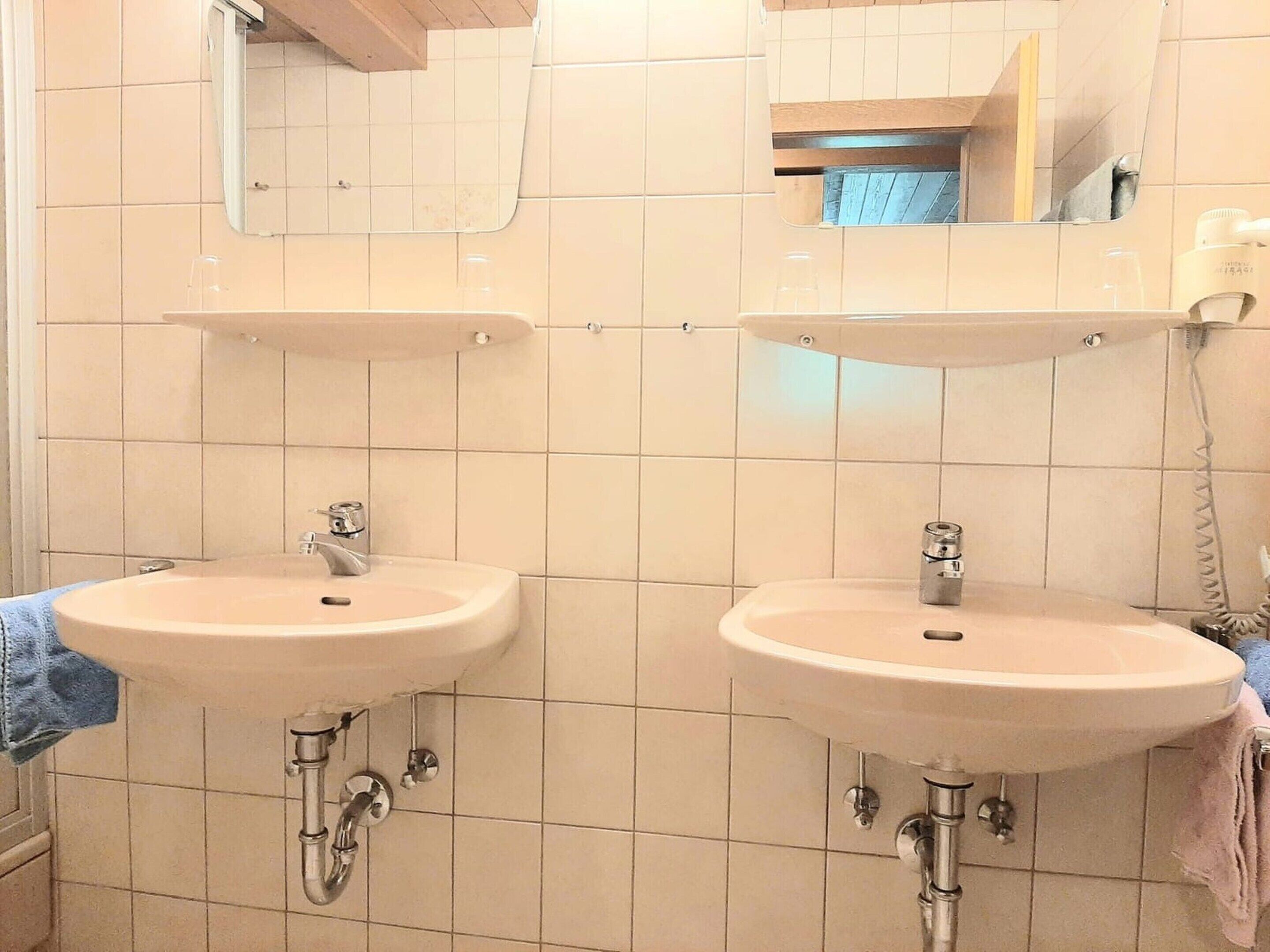 A bathroom with two sinks, a mirror, and a towel rack.