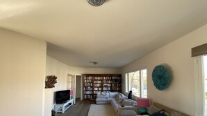 Un salon spacieux avec une grande bibliothèque, un canapé et une table à manger.