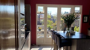 Une cuisine avec un coin repas, une vue à travers la porte vitrée et une plante en pot posée sur le comptoir.
