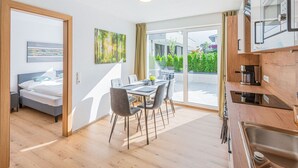 Ein modernes Hotelzimmer mit Essbereich, einer Küchenzeile und Blick auf den Garten.
