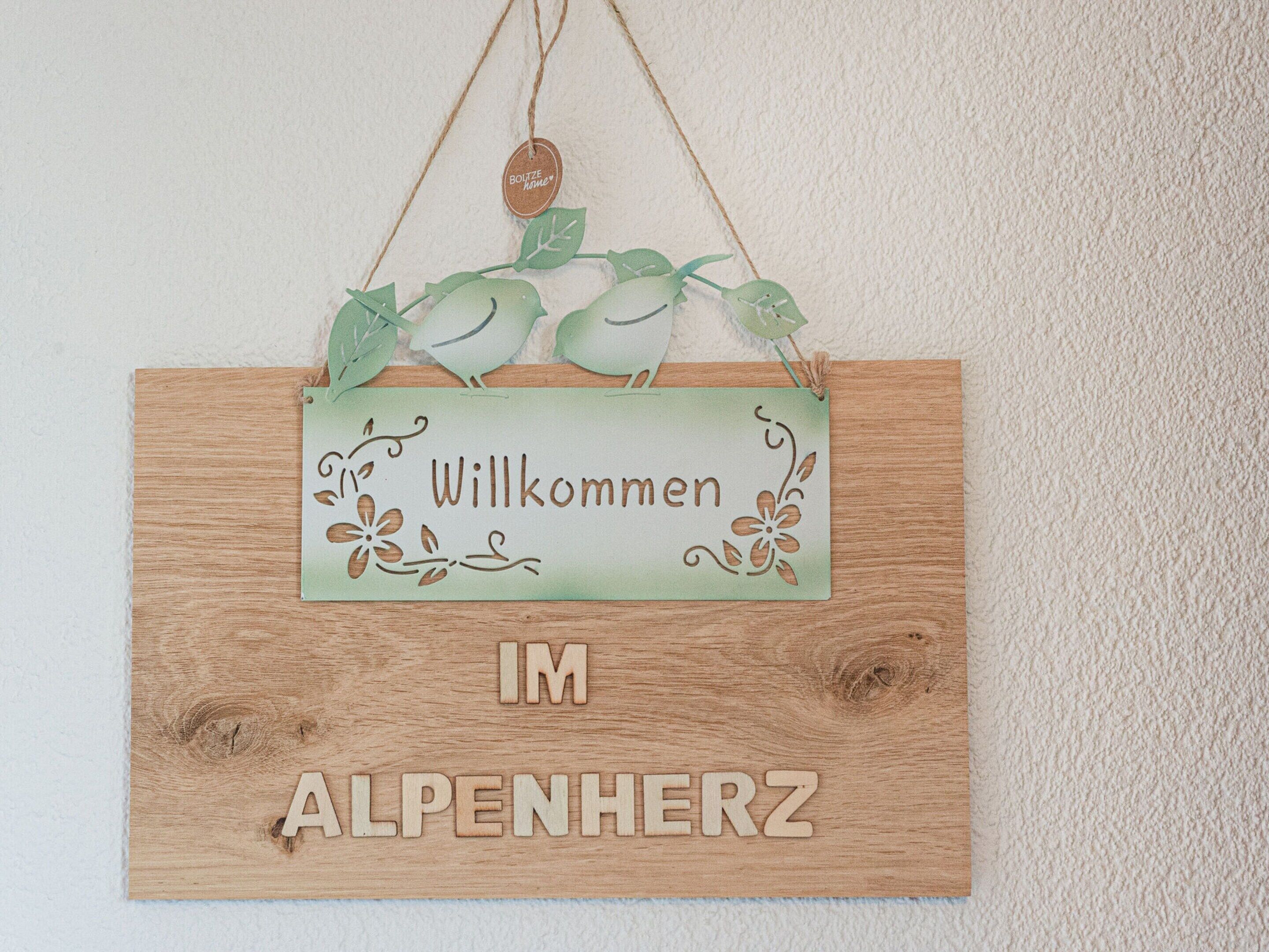 Un letrero de bienvenida con fondo de madera y detalles decorativos.