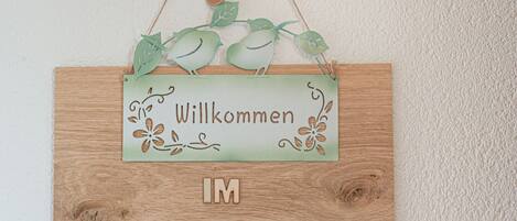 Un letrero de bienvenida con fondo de madera y detalles decorativos.