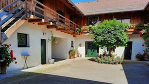 A wooden building with a staircase, a covered patio, and potted plants. - Loft-like Apartment With Swimming Pond (Scheibbs)