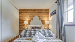 A bedroom with a wooden headboard, two bedside lamps, a fluffy bedspread, and a window with curtains. - Chalet in Mittersill by Ski Lift & Sauna (Mittersill)