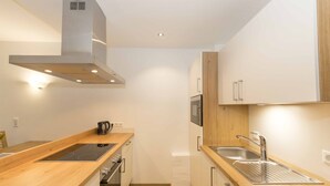 Una cocina compacta con encimeras de madera, electrodomésticos de acero inoxidable y armarios blancos.