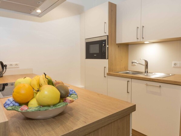 Una cocina moderna con encimera de madera, un cuenco de fruta, un microondas y un lavabo.