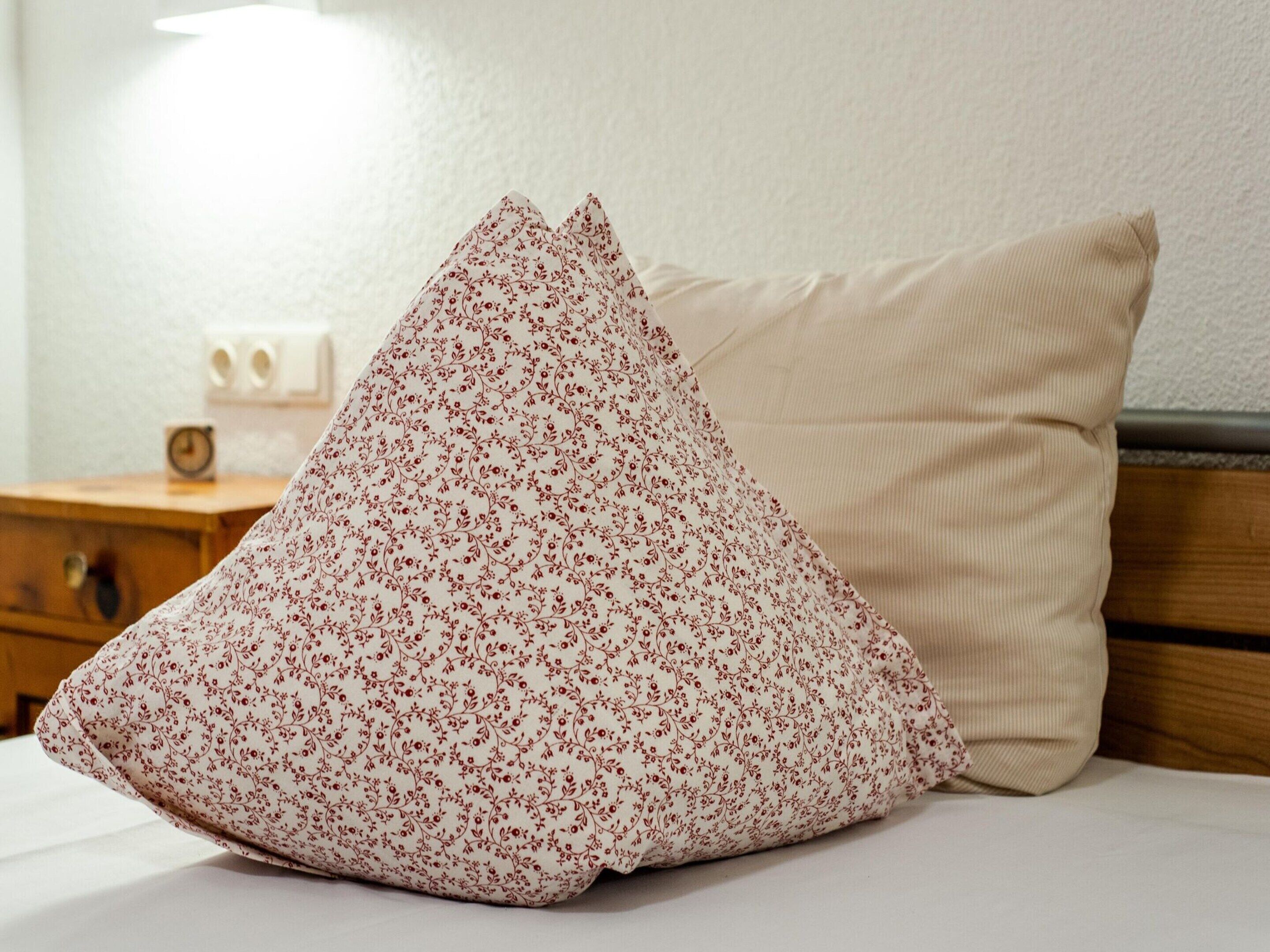 Ein Bett mit einem blumigen Kopfkissen und einem schlichten Kissen.