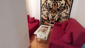 A modern living room with a red sofa, a white coffee table, and a large tiger mural on the wall. - Holiday Home Bodensdorf Near Ski & Lake (Steindorf am Ossiacher See)