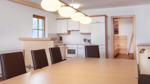 Uma cozinha moderna com armários brancos, bancada de madeira e luminária pendente.