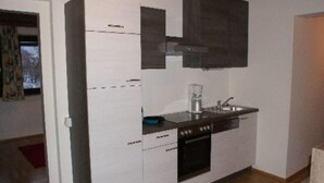 Eine kleine Küche mit weißen Schränken, einer schwarzen Arbeitsplatte und einem eingebauten Backofen.