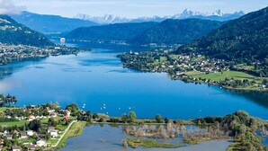 Panoramablick auf einen See, umgeben von Bergen und einer kleinen Stadt mit erkennbaren Gebäuden und Straßen.