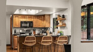 Una cocina moderna con armarios de madera, una isla central con taburetes y un ventanal con vistas.