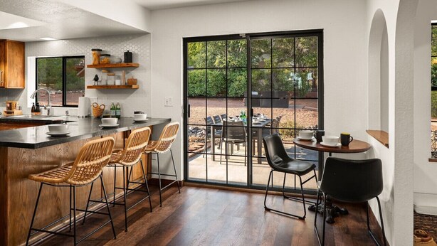 Una cocina moderna con una isla grande, taburetes de bar y una zona de comedor con mesa y sillas.
